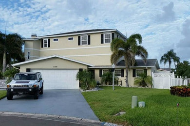 Large elegant beige two-story stucco exterior home photo in Tampa with a shingle roof