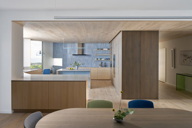 Eat-in kitchen - mid-sized contemporary u-shaped light wood floor and wood ceiling eat-in kitchen idea in Tampa with a drop-in sink, flat-panel cabinets, light wood cabinets, quartz countertops, blue backsplash, ceramic backsplash, paneled appliances, an island and gray countertops