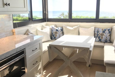 Open concept kitchen - mid-sized coastal l-shaped light wood floor and beige floor open concept kitchen idea in Jacksonville with a farmhouse sink, shaker cabinets, white cabinets, granite countertops, gray backsplash, porcelain backsplash, stainless steel appliances, an island and gray countertops