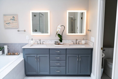 Inspiration for a mid-sized contemporary master bathroom in Portland with shaker cabinets, grey cabinets, a drop-in tub, a corner shower, a two-piece toilet, gray tile, ceramic tile, beige walls, porcelain floors, an undermount sink, engineered quartz benchtops, white floor, a hinged shower door, grey benchtops, a shower seat, a double vanity and a built-in vanity.