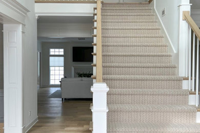 Large transitional carpeted straight wood railing and wall paneling staircase photo with carpeted risers