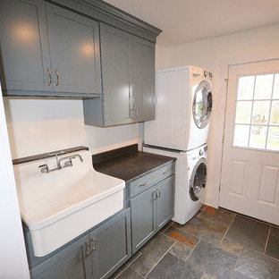 フィラデルフィアの中サイズのトランジショナルスタイルのおしゃれな家事室 (エプロンフロントシンク、フラットパネル扉のキャビネット、木材カウンター、白い壁、セラミックタイルの床、上下配置の洗濯機・乾燥機、グレーのキャビネット) の写真