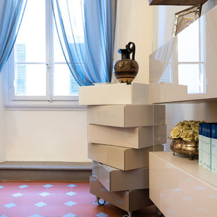 フィレンツェの大きいモダンスタイルのおしゃれな書斎 (白い壁、テラコッタタイルの床、標準型暖炉、コンクリートの暖炉まわり、自立型机、茶色い床) の写真