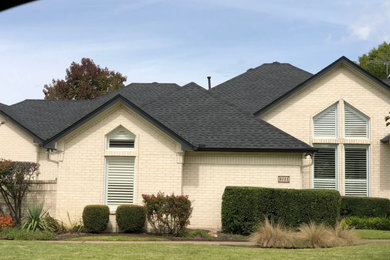 Photo of a large traditional two-storey brick beige house exterior in Dallas with a gable roof, a shingle roof and a grey roof.