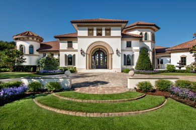 Photo of a large mediterranean one-storey stucco beige house exterior in Miami with a hip roof and a tile roof.