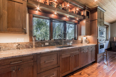 Example of a huge transitional l-shaped medium tone wood floor open concept kitchen design in Denver with shaker cabinets, granite countertops, stainless steel appliances and dark wood cabinets