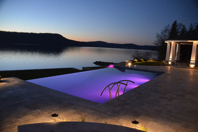 Pool - large contemporary backyard stone and rectangular infinity pool idea in Other