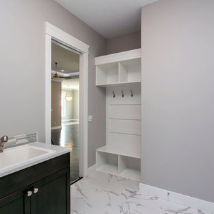 シアトルの中サイズのモダンスタイルのおしゃれな洗濯室 (ドロップインシンク、シェーカースタイル扉のキャビネット、濃色木目調キャビネット、クオーツストーンカウンター、グレーの壁、大理石の床、左右配置の洗濯機・乾燥機、白い床、白いキッチンカウンター) の写真