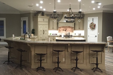 Huge elegant ceramic tile kitchen photo in Orlando with a farmhouse sink, recessed-panel cabinets, distressed cabinets, granite countertops, multicolored backsplash, stone tile backsplash, paneled appliances and two islands
