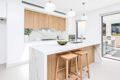 Design ideas for a mid-sized modern galley open plan kitchen in Sydney with porcelain floors, a drop-in sink, beaded inset cabinets, light wood cabinets, marble benchtops, white splashback, marble splashback, stainless steel appliances and with island.