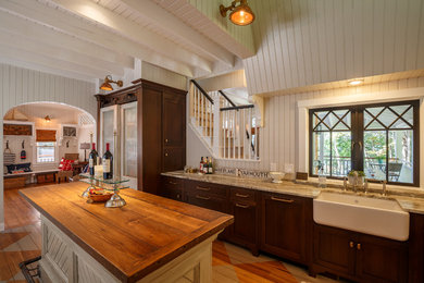 Design ideas for a mid-sized beach style u-shaped kitchen in Portland Maine with a farmhouse sink, glass-front cabinets, marble benchtops, white splashback, subway tile splashback, stainless steel appliances, painted wood floors, with island and dark wood cabinets.
