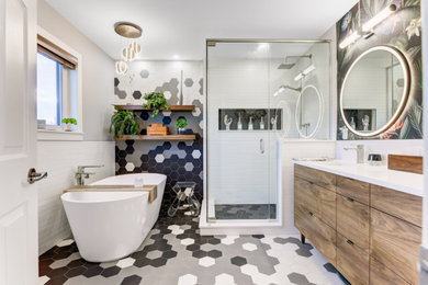 This is an example of a contemporary master bathroom in Edmonton with flat-panel cabinets, brown cabinets, a freestanding tub, a corner shower, a one-piece toilet, white tile, ceramic tile, grey walls, ceramic floors, an undermount sink, engineered quartz benchtops, black floor, a hinged shower door, white benchtops, a niche, a double vanity, a freestanding vanity and wallpaper.