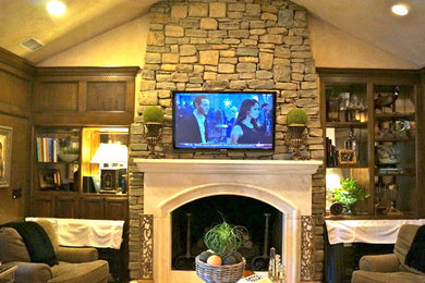 Family room - mid-sized traditional enclosed family room idea in Oklahoma City with beige walls, a standard fireplace, a stone fireplace and a wall-mounted tv