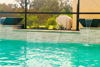 Foto de piscinas y jacuzzis alargados actuales grandes a medida en patio trasero con adoquines de hormigón