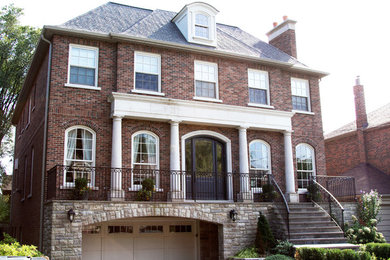 Design ideas for a two-storey red exterior in Toronto with stone veneer.