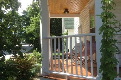 This is an example of a mid-sized traditional front porch design in Burlington with decking and a roof extension.