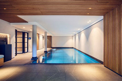 Imagen de piscina contemporánea interior y rectangular con suelo de baldosas