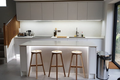 Cette image montre une cuisine ouverte design en U de taille moyenne avec un sol en carrelage de porcelaine, îlot et un sol gris.