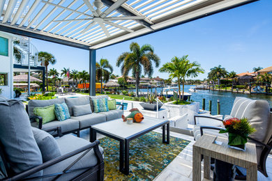 Design ideas for a large contemporary backyard patio in Miami with natural stone pavers and a pergola.
