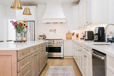 Eat-in kitchen - large transitional l-shaped light wood floor and beige floor eat-in kitchen idea in Philadelphia with an undermount sink, shaker cabinets, medium tone wood cabinets, quartz countertops, white backsplash, subway tile backsplash, stainless steel appliances, an island and white countertops