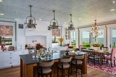 Large elegant l-shaped medium tone wood floor, brown floor and wallpaper ceiling eat-in kitchen photo in Tampa with an undermount sink, shaker cabinets, white cabinets, marble countertops, white backsplash, subway tile backsplash, stainless steel appliances, an island and black countertops