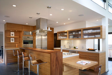 Design ideas for a large modern u-shaped eat-in kitchen in Los Angeles with an undermount sink, flat-panel cabinets, dark wood cabinets, quartz benchtops, beige splashback, glass sheet splashback, stainless steel appliances, slate floors and with island.