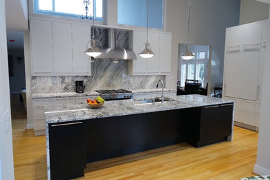 Mid-sized trendy light wood floor eat-in kitchen photo in Raleigh with flat-panel cabinets, white cabinets, stainless steel appliances and an island