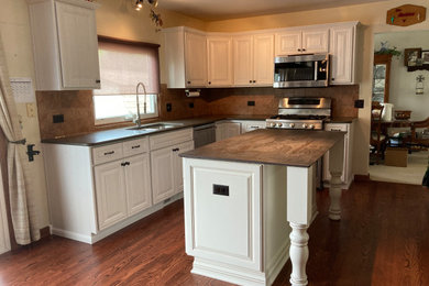 На фото: угловая кухня среднего размера в классическом стиле с обеденным столом, белыми фасадами и островом с