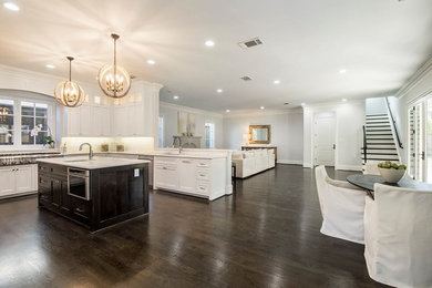 Inspiration for a large transitional u-shaped dark wood floor eat-in kitchen remodel in Dallas with white cabinets, white backsplash, stainless steel appliances and an island