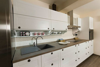 Mid-sized elegant single-wall medium tone wood floor enclosed kitchen photo in Other with a single-bowl sink, flat-panel cabinets, white cabinets, white backsplash, ceramic backsplash, black appliances and no island
