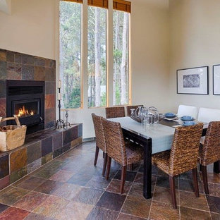 Imagen de comedor tradicional renovado con suelo de pizarra, chimenea de esquina y marco de chimenea de baldosas y/o azulejos