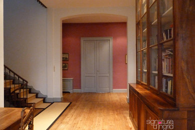 Aménagement d'un couloir classique avec un mur rose et parquet clair.