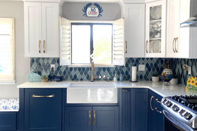 Example of a mid-sized beach style l-shaped vinyl floor and multicolored floor kitchen pantry design in Other with a farmhouse sink, shaker cabinets, blue cabinets, quartz countertops, multicolored backsplash, glass tile backsplash, stainless steel appliances, no island and white countertops