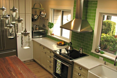 Inspiration for a mid-sized traditional single-wall eat-in kitchen in Vancouver with shaker cabinets, white cabinets, green splashback, glass tile splashback, stainless steel appliances and with island.