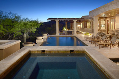 This is an example of a mid-sized mediterranean backyard rectangular infinity pool in Phoenix with concrete pavers.