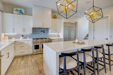 Example of a large minimalist l-shaped porcelain tile and brown floor eat-in kitchen design in Austin with an undermount sink, flat-panel cabinets, white cabinets, quartz countertops, blue backsplash, porcelain backsplash, stainless steel appliances, an island and white countertops