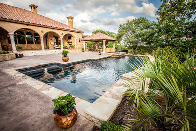 Example of a large tuscan backyard stone and rectangular hot tub design in Austin