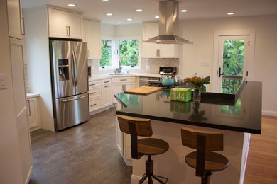 Photo of a mid-sized contemporary u-shaped eat-in kitchen in San Francisco with shaker cabinets, white cabinets, quartz benchtops, grey splashback, glass tile splashback, stainless steel appliances, light hardwood floors, with island, an undermount sink and brown floor.