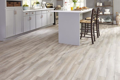 Example of a mid-sized arts and crafts single-wall light wood floor and beige floor eat-in kitchen design in Orange County with a drop-in sink, shaker cabinets, white cabinets, solid surface countertops, an island and white countertops