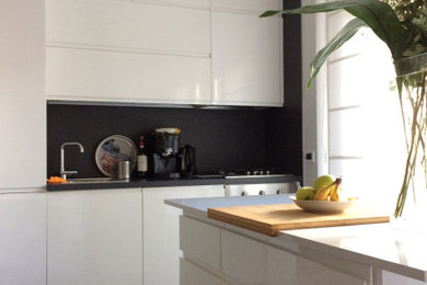 ローマにある小さなモダンスタイルのおしゃれなキッチン (シングルシンク、フラットパネル扉のキャビネット、白いキャビネット、珪岩カウンター、黒いキッチンパネル、磁器タイルのキッチンパネル、黒い調理設備、磁器タイルの床、グレーの床、白いキッチンカウンター) の写真