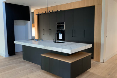 Modern single-wall eat-in kitchen in Melbourne with recessed-panel cabinets, black cabinets, quartz benchtops and with island.