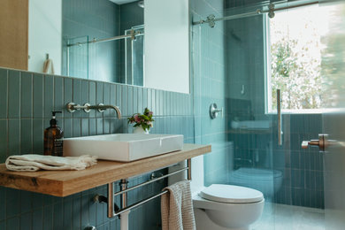 Example of a small minimalist kids' blue tile ceramic tile, gray floor and single-sink bathroom design in Austin with a one-piece toilet, a vessel sink, wood countertops and a floating vanity
