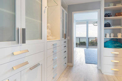 Mid-sized modern gender-neutral walk-in wardrobe in Miami with white cabinets.