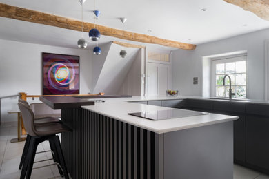 Design ideas for a medium sized contemporary u-shaped enclosed kitchen in Gloucestershire with an integrated sink, flat-panel cabinets, grey cabinets, quartz worktops, black appliances, porcelain flooring, an island and white floors.