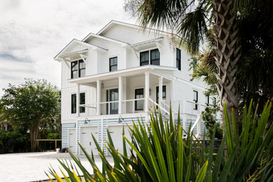 Large beach style white three-story exterior home photo in Charleston with a shingle roof and a black roof
