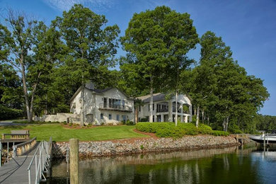 Example of a large trendy white two-story stucco house exterior design in Other with a hip roof and a shingle roof