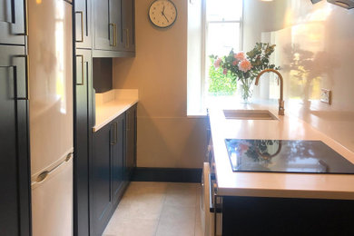 This is an example of a medium sized traditional galley enclosed kitchen in Other with shaker cabinets, blue cabinets, quartz worktops, white splashback, white appliances and white worktops.