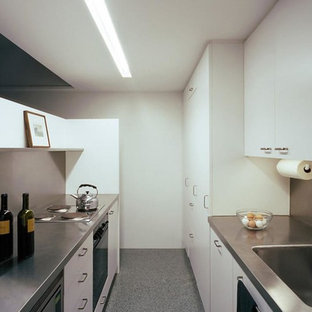 Small modern kitchen pantry ideas - Kitchen pantry - small modern single-wall concrete floor kitchen pantry idea in Montreal with an integrated sink, flat-panel cabinets, white cabinets, stainless steel countertops, metallic backsplash, metal backsplash, stainless steel appliances and an island