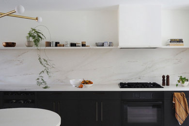 Immagine di una cucina abitabile contemporanea con paraspruzzi in marmo e elettrodomestici neri