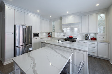 Large transitional l-shaped porcelain tile and gray floor eat-in kitchen photo in Toronto with an undermount sink, shaker cabinets, white cabinets, quartz countertops, white backsplash, marble backsplash, stainless steel appliances and an island